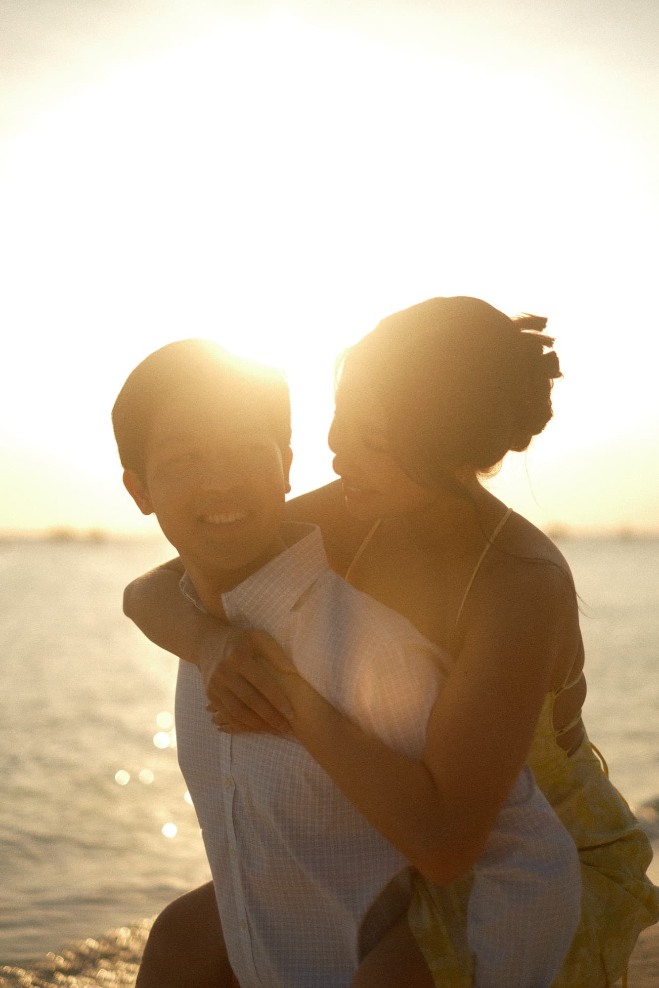 Backlit couple embracing by the water at golden hour